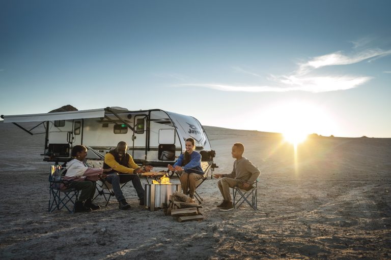 Family around fire while camping with their travel trailer