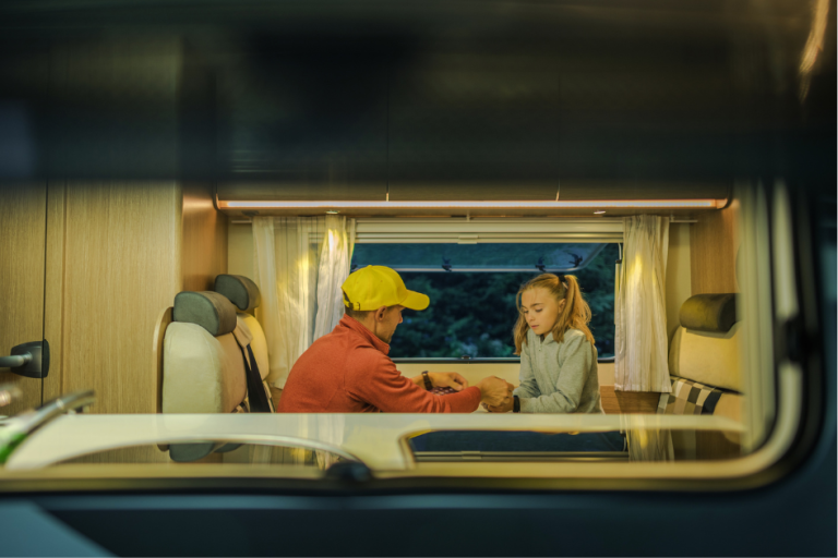 Father and Daughter seen sitting at a table through their RV window