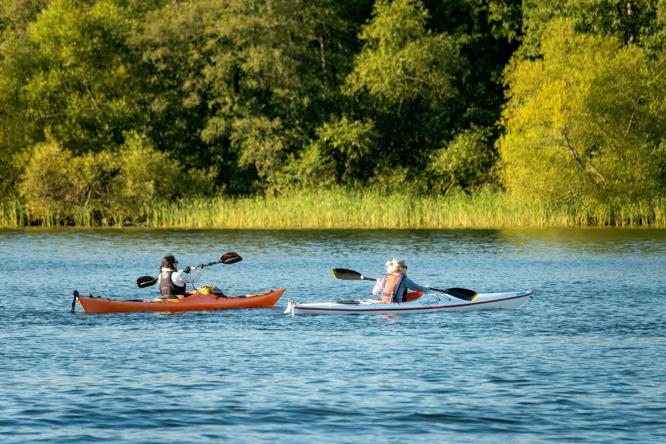 Friends kayak on Lake Superior on a bright, sunny day.