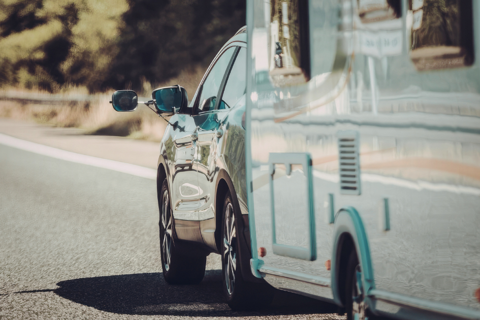 A car tows a travel trailer behind it on the road. 