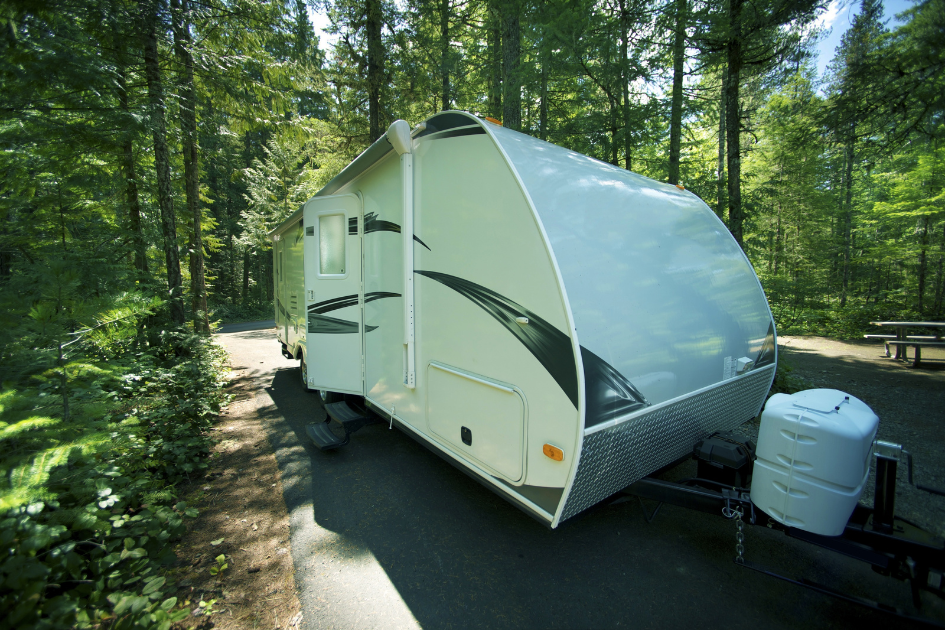A travel trailer parked in a tree lined camp spot