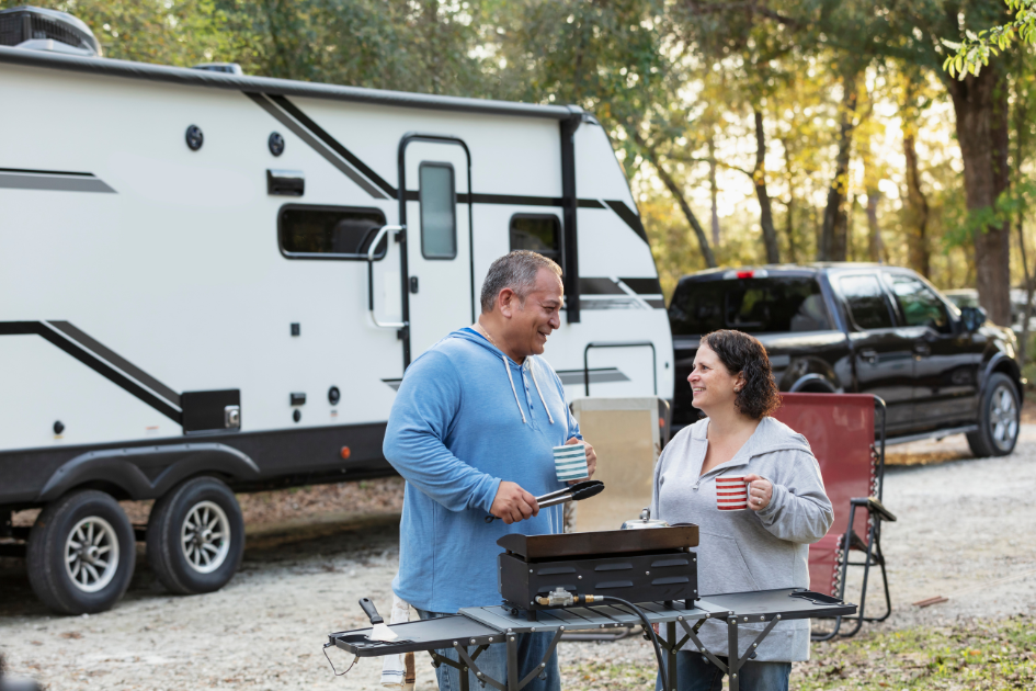 Couple cooks breakfast outside their parked travel trailer