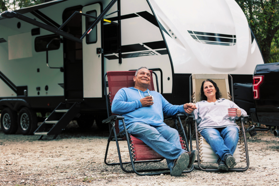 A couple sits in front of their parked RV