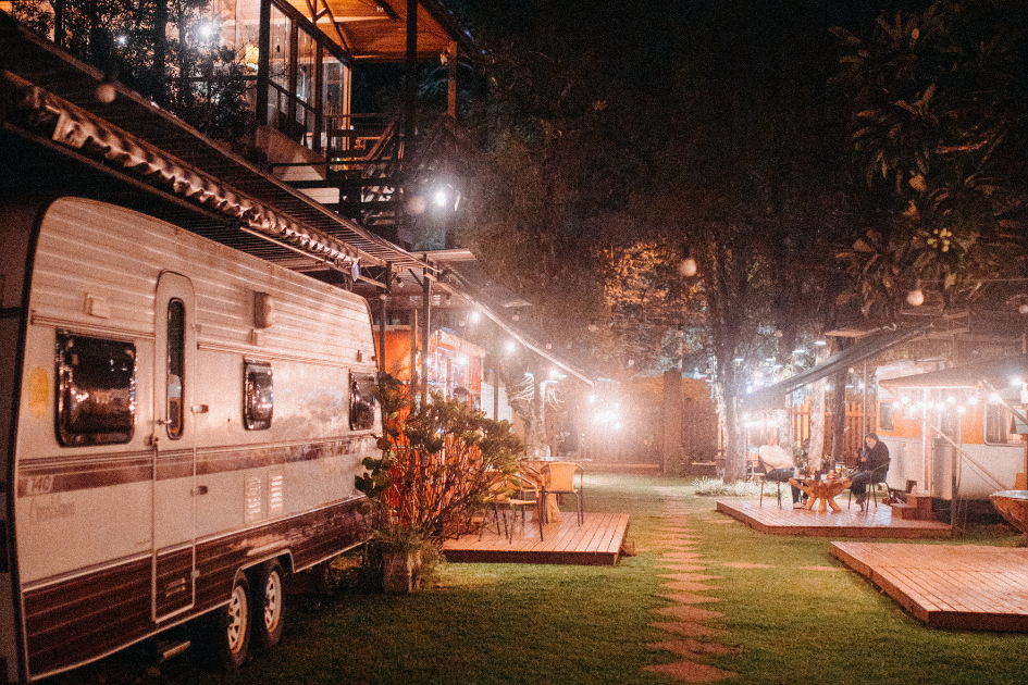 A seasonal RV park with several RVs parked and linked together with fairy lights between campsites