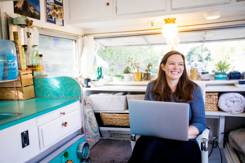 A woman smiles in her RV surrounded by clever storage solutions