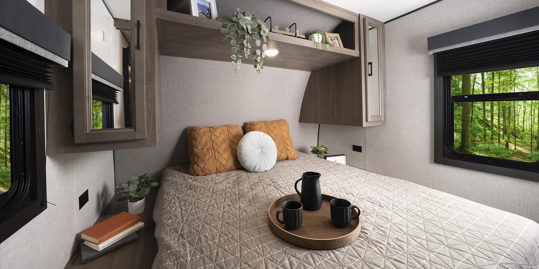 A queen bed with built-in overhead storage. There are windows on either side of the bed.