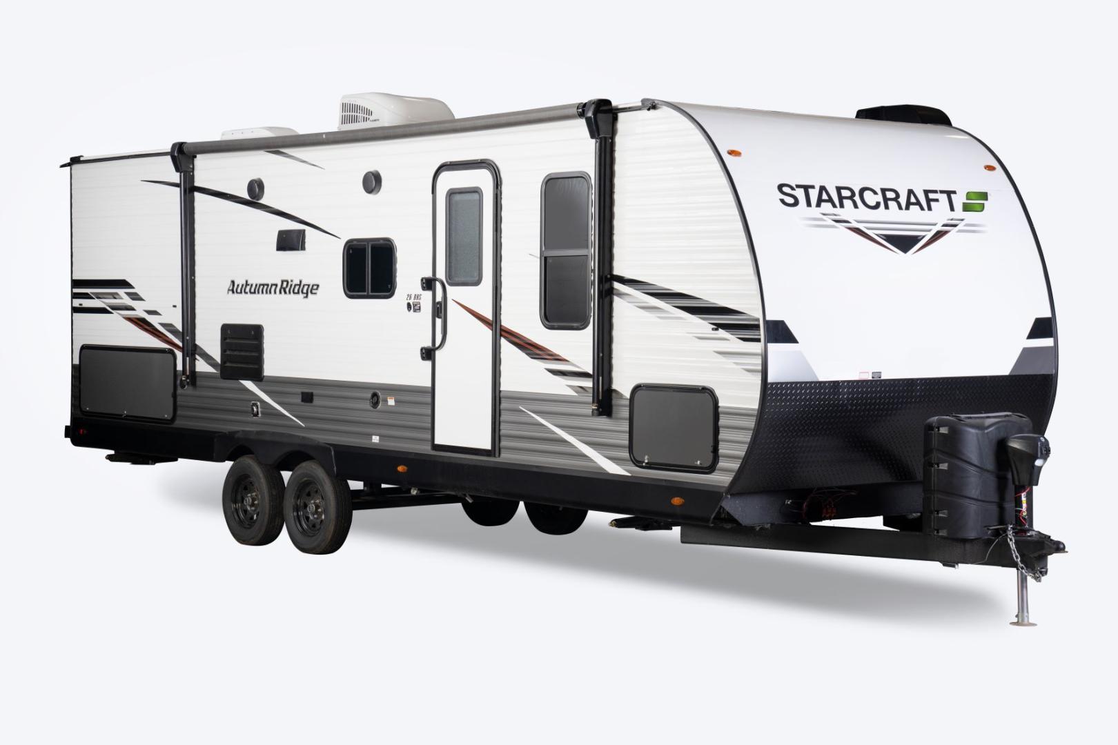 Exterior shot of the Starcraft Autumn Ridge travel trailer. It is white with grey and black detailing, including the manufacturer's name on the front. 